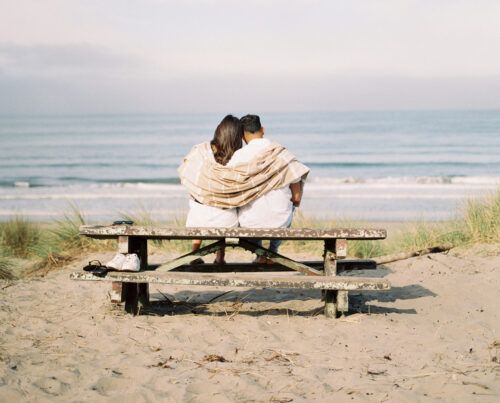 couple sitting on picnic table at the beach